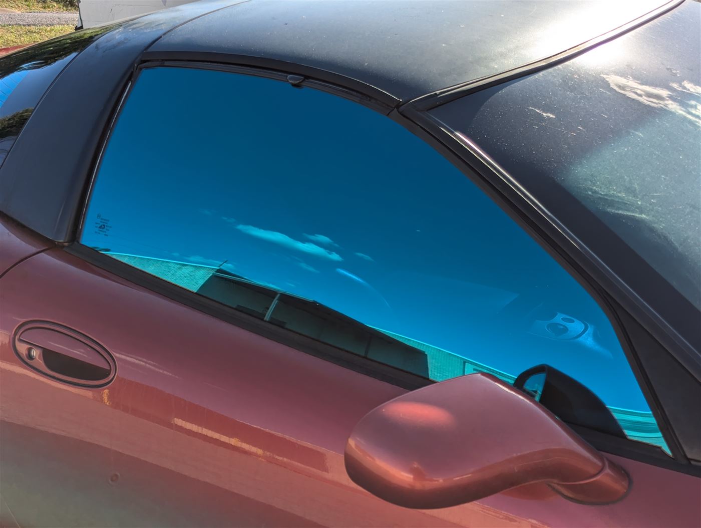 Close-up of tinted door glass on a red Corvette